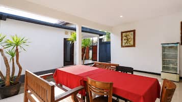 A dining area with a table set for four, surrounded by wooden chairs, with a red tablecloth.