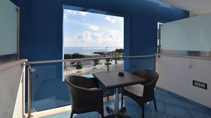 A balcony with a view of the sea, a table, and two chairs. - Damavi Hotel (San Foca)