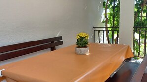 A table with a yellow tablecloth, a bench, and a potted plant with yellow flowers. - Stunning apartment in Palit with WiFi (Palit)