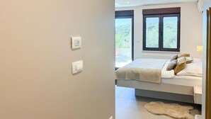 A bedroom with a bed, a window, and a thermostat on the wall. - Stunning apartment in Palit with WiFi (Palit)
