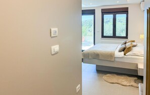 Ein Schlafzimmer mit einem Bett, einem Fenster und einem Thermostat an der Wand.