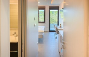 Ein modernes Hotelzimmer mit einem Bett, einem Schreibtisch und Blick ins Freie durch große Fenster.