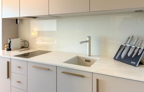 Eine moderne Küche mit weißer Arbeitsplatte, einem Spülbecken und einem Messerblock.