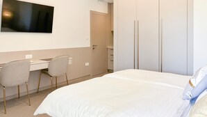 Ein Hotelzimmer mit einem Bett, einem Schreibtisch mit zwei Stühlen, einem Fernseher und einem Kleiderschrank.