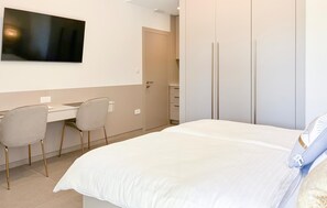 A hotel room with a bed, a desk with two chairs, a television, and a wardrobe. - Gorgeous apartment in Palit (Palit)