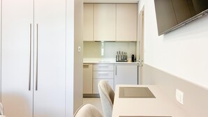 A compact kitchen with white cabinets, a countertop, and a chair. - Lovely apartment in Palit with WiFi (Palit)