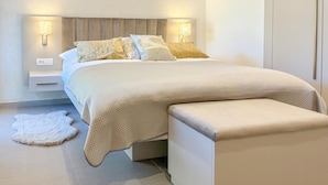 A modern bedroom with a bed, bedside lamps, a nightstand, and a bench. - Lovely apartment in Palit with WiFi (Palit)