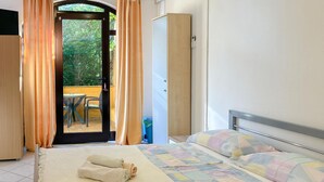 Un dormitorio con cama, armario y vistas a un espacio exterior con mesa y sillas.