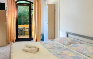 Ein Schlafzimmer mit Bett, Schrank und Blick auf einen Außenbereich mit Tisch und Stühlen.