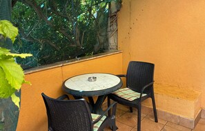 A small outdoor seating area with a round table and two chairs, a metal bowl on the table, and a window with a view of trees. - Stunning apartment in Lopar with WiFi (Lopar)