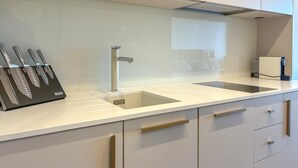 A modern kitchen with a white countertop, a stainless steel faucet, and a knife block. - Nice apartment in Palit with WiFi (Palit)