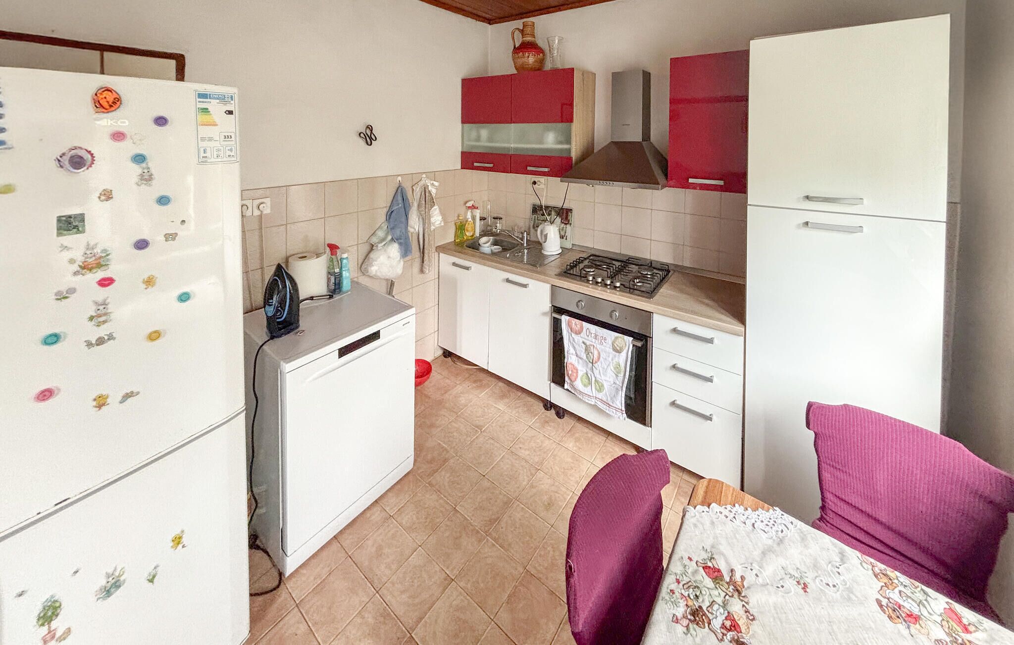 Eine kleine Küche mit Kühlschrank, Herd, Backofen und Spüle.