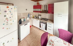 Eine kleine Küche mit Kühlschrank, Herd, Backofen und Spüle.