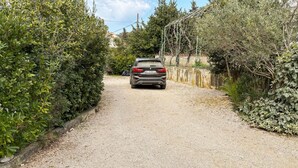 Un chemin de gravier mène à un bâtiment devant lequel une voiture est garée.