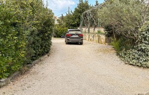 Ein Feldweg, der zu einem Gebäude führt, vor dem ein Auto geparkt ist.