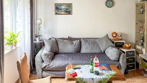 Un salon chaleureux avec un canapé gris, une petite table sur laquelle se trouvent une bouteille, une télécommande et un livre.