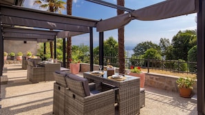 An outdoor patio with wicker furniture, a covered area, and potted plants. - Gorgeous apartment in Lovran with WiFi (Lovran)