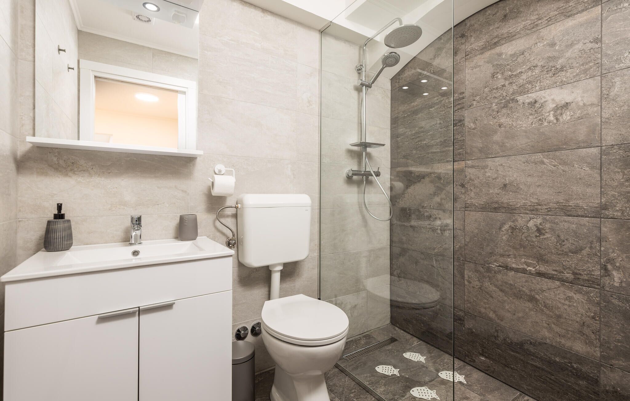 A modern bathroom with a shower, toilet, and sink.