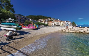 Une plage de galets bordée d’embarcations aux couleurs vives et d’une côte rocheuse.