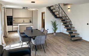 A modern kitchen with white cabinets, a dining area with a table and chairs, and a spiral staircase. - Stunning home in Opatija-Moscenicka (Opatija-Moscenicka)