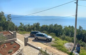 A coastal property with two parked cars, a stone pathway, and a view of the sea and mountains. - Stunning home in Opatija-Moscenicka (Opatija-Moscenicka)