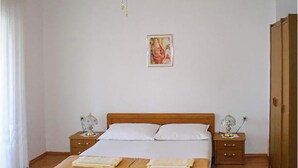 A bedroom with a wooden bed, white bedding, two bedside tables with lamps, and a framed picture on the wall. - Lovely apartment in Sveti Juraj with WiFi (Sveti Juraj)