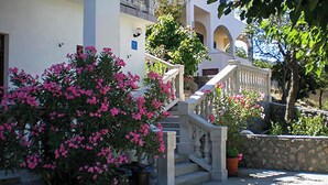 A building with a staircase, a stone wall, and pink flowering plants. - Lovely apartment in Sveti Juraj with WiFi (Sveti Juraj)