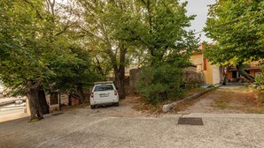 A white car parked on a gravel driveway with trees and a building in the background. - Gorgeous apartment in Karlobag with WiFi (Karlobag)