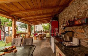 A covered outdoor dining area with wooden furniture and a stone wall. - Gorgeous apartment in Karlobag with WiFi (Karlobag)