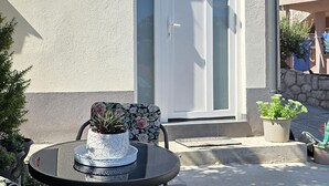 An outdoor seating area with a table and chairs, a potted plant, and a door in the background. - Lovely apartment in Karlobag with WiFi (Karlobag)