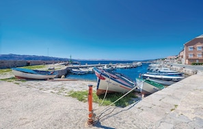 Ein Hafen mit vertäuten Booten, einer Steinmauer und Gebäuden im Hintergrund.