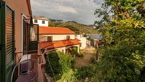 A coastal building with a red-tiled roof, a balcony with a chair, and a view of the sea and mountains. - Awesome apartment in Karlobag with WiFi (Karlobag)