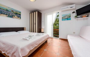 A hotel room with a bed, a seating area, a painting, an air conditioning unit, and a television. - Awesome apartment in Karlobag with WiFi (Karlobag)