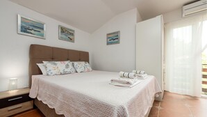 A bedroom with a bed, pillows, a bedside table, and a window with curtains. - Awesome apartment in Karlobag with WiFi (Karlobag)