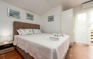 A bedroom with a bed, pillows, a bedside table, and a window with curtains.