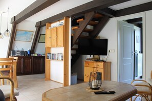 A dining area with a table, chairs, and a television in the background. - gemütliche Unterkunft in Burhave (Fedderwardersiel)