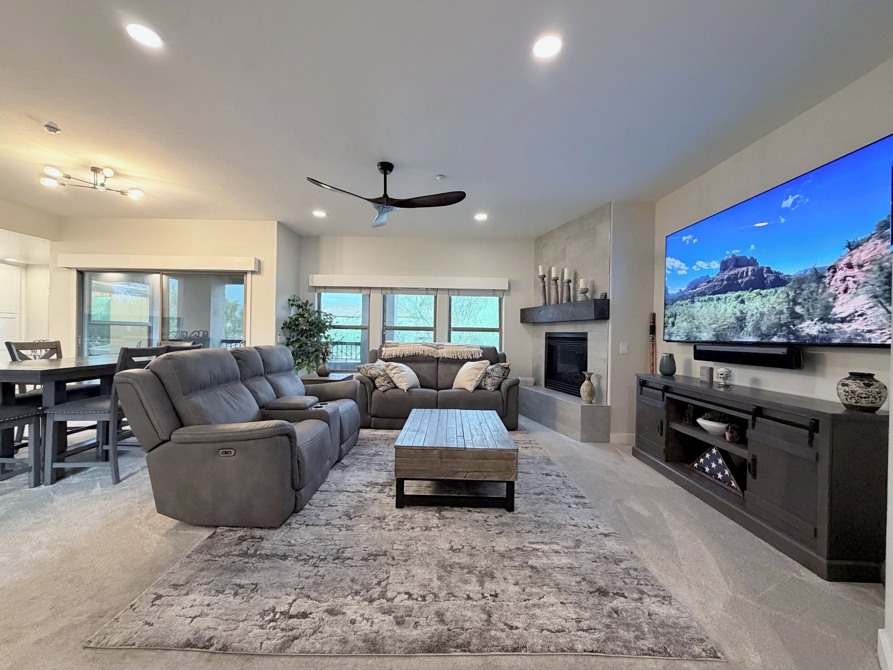 A modern living room with a sectional sofa, a coffee table, a fireplace, and a large flat-screen TV.