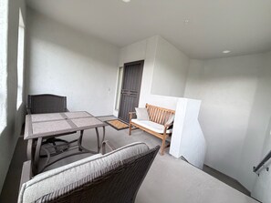 A small, enclosed balcony with a table and chairs, a wooden bench, and a door. - Cozy 3-bedroom condo with AC in awesome Cave Creek AZ (Cave Creek)