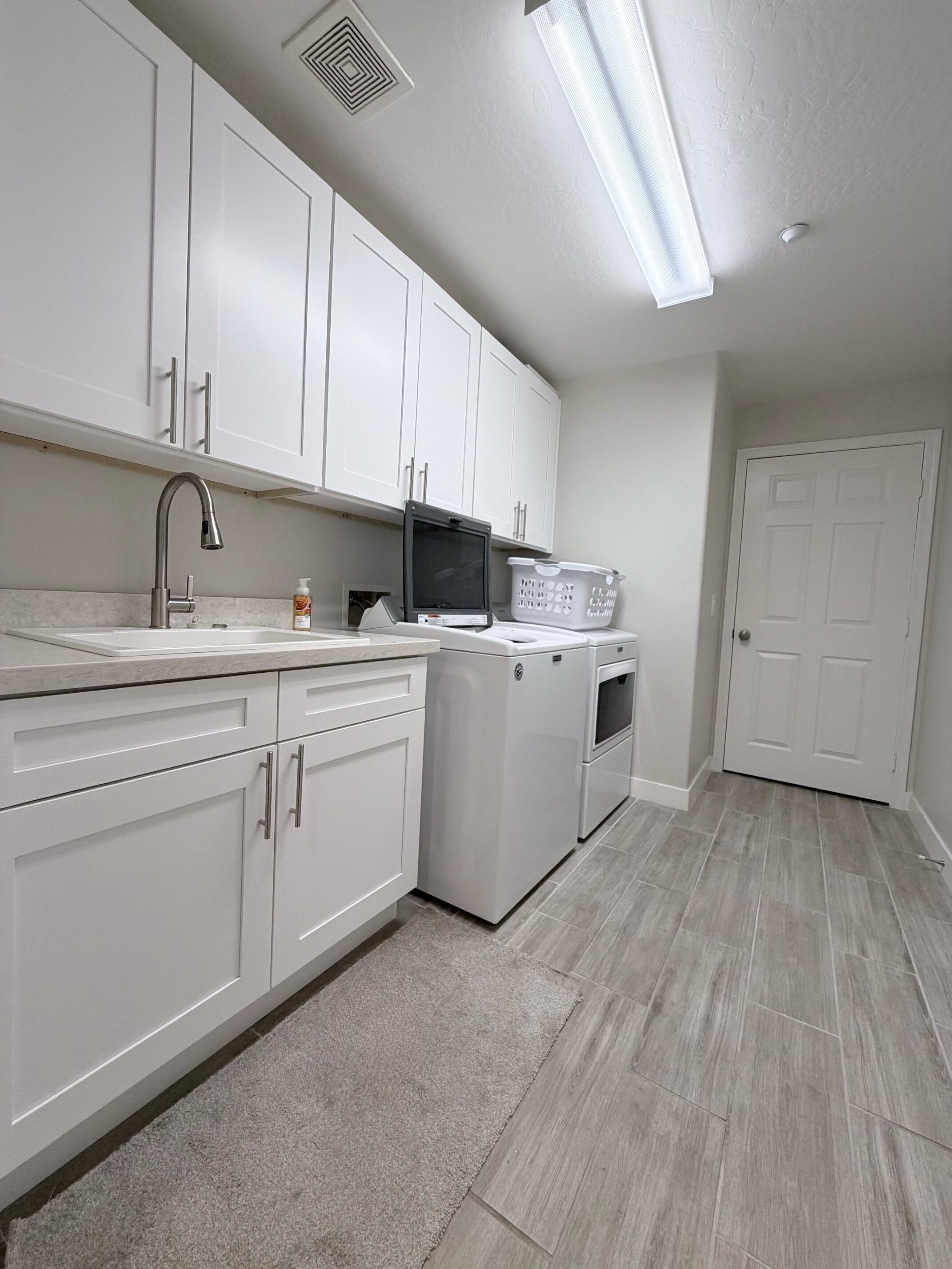 A kitchen with white cabinets, a stainless steel sink, a microwave, and a dishwasher.
