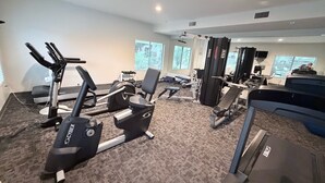 Un gimnasio con cintas de correr, máquinas de pesas y bancos.