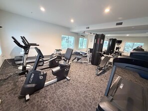 Ein Fitnessstudio mit Laufbändern, Kraftgeräten und Bänken.