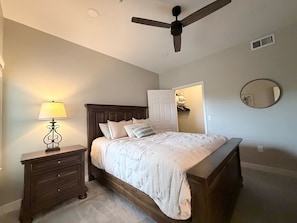 A bedroom with a bed, nightstand, lamp, ceiling fan, closet, and mirror. - Cozy 3-bedroom condo with AC in awesome Cave Creek AZ (Cave Creek)