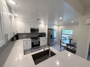 A modern kitchen with white cabinetry, stainless steel appliances, and a marble countertop. - Cozy 3-bedroom condo with AC in awesome Cave Creek AZ (Cave Creek)