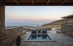 Una piscina de piedra con asientos y vistas al mar.