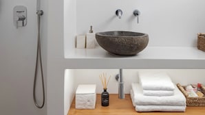 A modern bathroom with a stone sink, a handheld showerhead, and a wooden vanity. - Fos Suite by Vivian Horizon Tinos, Vivian Suites Tinos (Tinos)