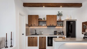 Eine kompakte Küche mit Holzschränken, einem schwarzen Kühlschrank und einem integriertem Geschirrspüler.