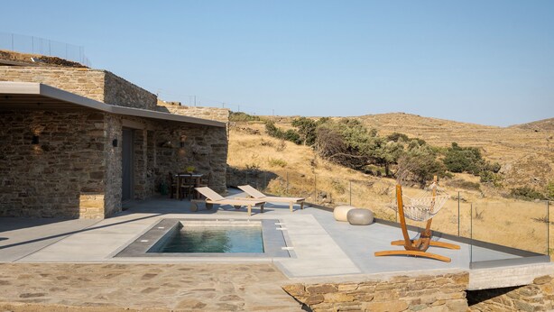 Ein Gebäude aus Stein mit einem Pool, Sitzgelegenheiten im Freien und Blick auf die Hügel.