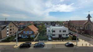 A residential area with a mix of modern and traditional architecture, including a church with a prominent steeple. - Apartment on the coast for 6 people (MIDDELKERKE)