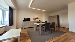A modern living room with a dining area, a flat-screen TV, and a wooden cabinet. - Apartment on the coast for 6 people (MIDDELKERKE)
