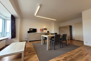 A modern living room with a dining area, a flat-screen TV, and a wooden cabinet. - Apartment on the coast for 6 people (MIDDELKERKE)